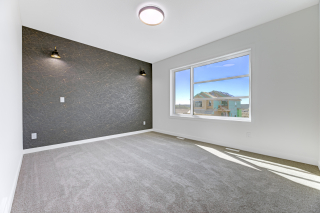 Modern bedroom with textured black feature wall, grey carpet, and large window offering natural light in a Vita Homes Build