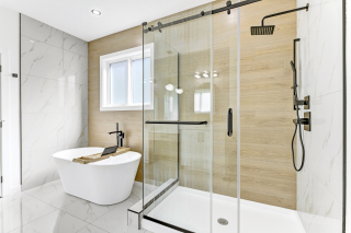Spa-inspired ensuite bathroom with freestanding soaker tub, walk-in glass shower, and wood-accent wall in a Vita Homes model in Beaumont