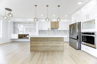 Bright modern kitchen in the Aria model by Vita Homes with sleek white cabinetry, waterfall island, marble backsplash, and built in wine rack