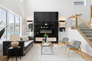 Modern living room in the Bellagio model by Vita Homes featuring a luxurious fireplace, high ceilings, and side lights - custom home in Edmonton and Beaumont