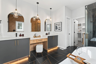 Luxurious master ensuite featuring his and her sinks and a central makeup desk in the Bellagio with Bar design