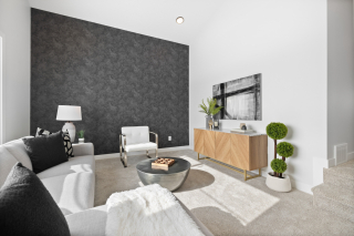 Modern bonus room featuring a sleek black feature wall, cozy white sectional, stylish coffee table, and media console in a Vita Homes build in Edmonton or Beaumont