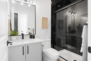 Elegant full bathroom in the Bellagio model by Vita Homes, featuring a sleek white vanity, black fixtures, and modern tile shower — custom homes available in Edmonton and Beaumont