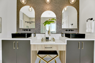 Luxury double vanity in the Venetian model by Vita Homes with black vessel sinks, arches mirrors, and gold-accented stool - new homes in edmonton, beaumont, and leduc